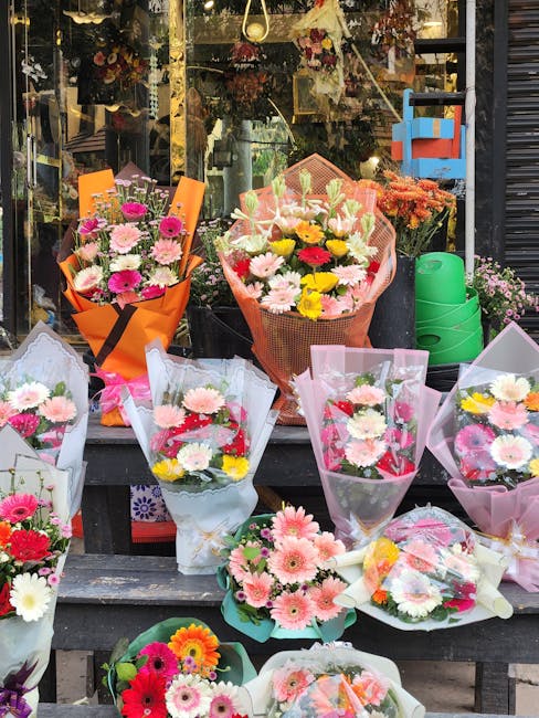 A vibrant display of fresh floral bouquets arranged outdoors in front of a flower shop window at flowerdeliverywoodgreen.co.uk, featuring a variety of colorful flowers such as pink gerbera daisies, wh
