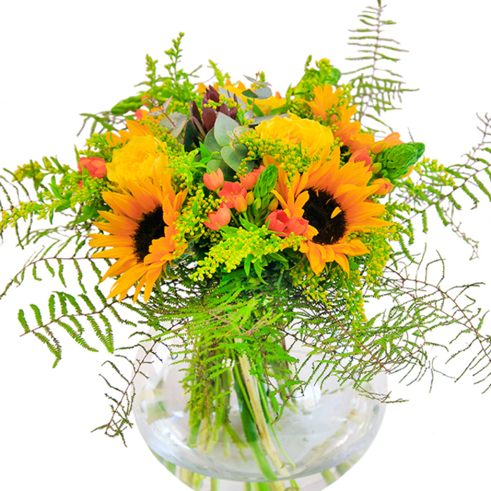 This stunning bouquet channels the bustle and brightness of Wood Green's main streets, featuring radiant sunflowers and buttery yellow garden roses presented in a chic, clear globe vase. The sunflowers, bold and open, with their golden petals and velvety brown centers, are reminiscent of late-season blooms gathered from Muswell Hill's leafy lanes. Surrounding them are elegant yellow roses, their petals layered in delicate spirals that feel both modern and timeless. The vivid contrast of small, scarlet Hypericum berries peeks through the arrangement, energizing the design and celebrating the area's dynamic diversity. Soft, feathery greenery-fern fronds, tiny clusters of goldenrod, and silvery-green eucalyptus-flows through the bouquet, adding depth, movement, and a rustic charm. The water-filled vase showcases the stems' natural beauty and hints at the fresh, subtle fragrance drifting upwards. Whether illuminating a Wood Green flat or gracing a celebratory table near Noel Park, this arrangement is a joyful tribute to life's happiest moments. Every detail highlights the artistic expertise of Wood Green's florists and the enduring appeal of seasonal flowers expertly arranged for local delivery.